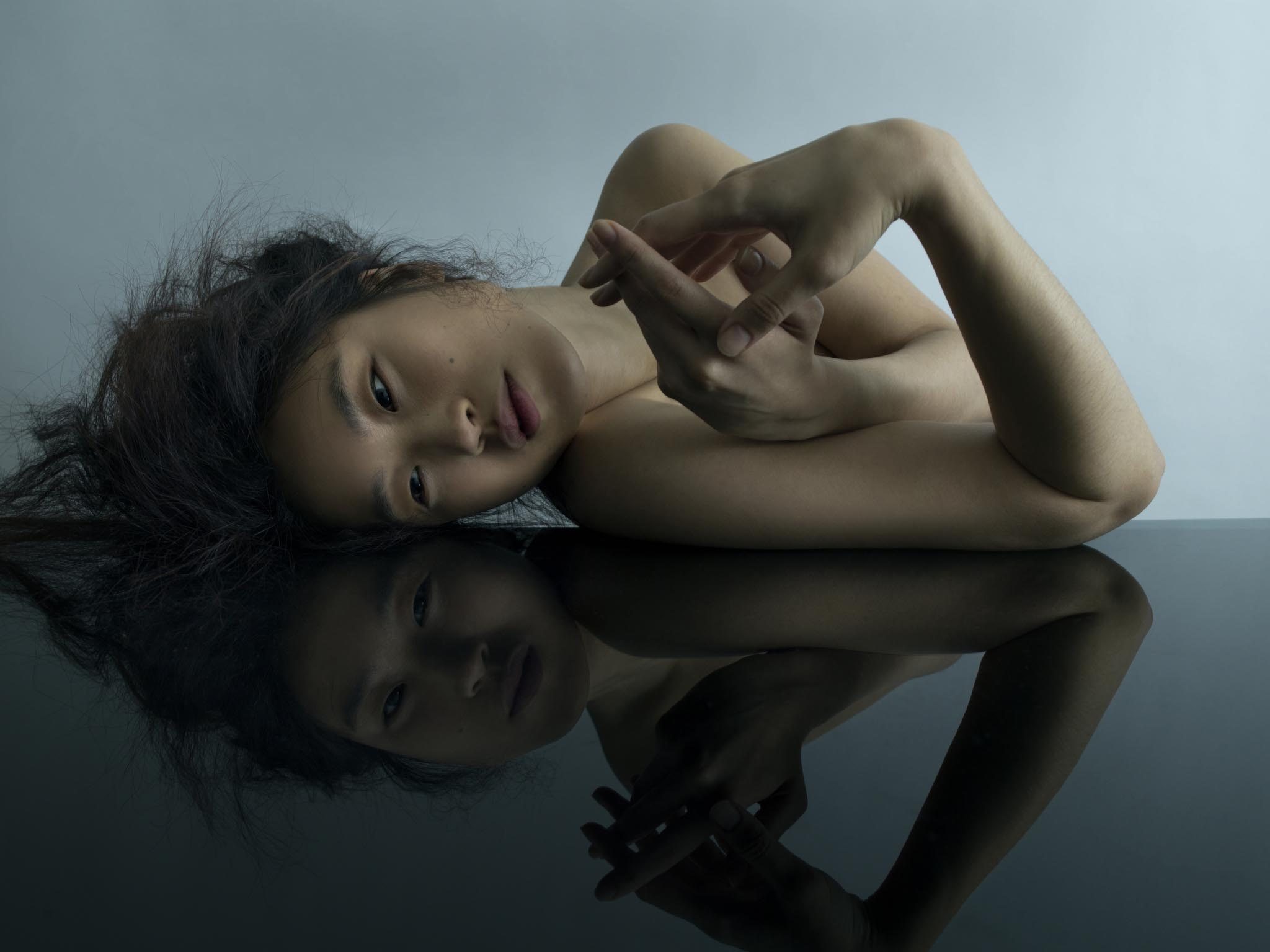 An asian model with nude make up laying on a set for a beauty makeup shot by Chris Singer chrissinger